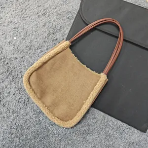 Close-up of brown suede bag with fluffy fleece trim and slim faux leather handles