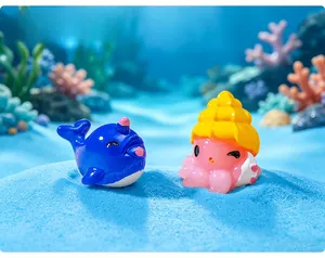 Miniature resin blue dolphin and pink octopus figurines in a deep sea blue sand scene