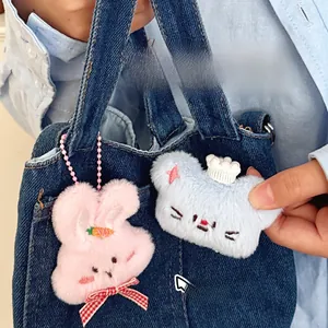 Pluchen knuffelhanger met borduursel aan een spijkerbroekzak met roze ketting