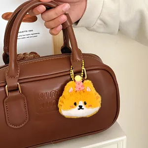 Detail van een schattige oranje pluche kattenhanger aan een donkerbruine leren handtas