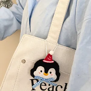 Schattige pinguïn pluche hanger met kerstmuts en blauwe strik op een canvas tas detail