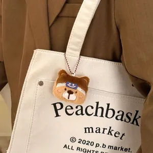 Schattige bruine pluchen berenhoofd hanger met blauw lachend gezicht op een canvas tas