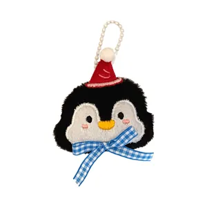 Schattige pluche pinguïn hanger met rode kerstmuts en blauwe geruite strik