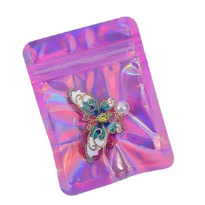 Golden butterfly brooch with white teal enamel in a colorful laser holographic resealable bag