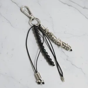 Close-up of metal beaded keychain with irregular silver beads and black stones.