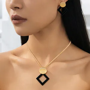 Detail of elegant gold snake chain necklace and geometric black diamond pendant on model