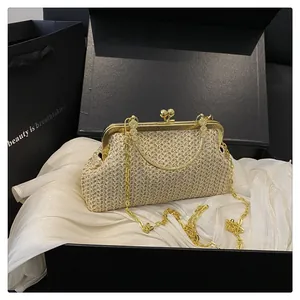 Detail of beige woven shell bag with gold metal frame, ball clasp and chain strap