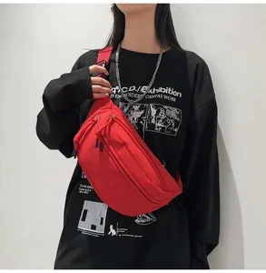 Dettaglio della borsa a tracolla rossa in nylon con doppia cerniera indossata da un modello