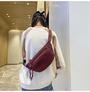 Vista posteriore del modello con borsa a tracolla rosso vino e tasche multiple con zip