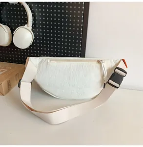 Dettaglio del retro della borsa a tracolla crema con tasca con zip e ampia cinghia