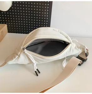 Dettaglio del marsupio in tessuto bianco crema con zip e tracolla regolabile
