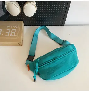 Dettaglio della borsa pettorale in nylon blu lago con tracolla regolabile ed etichetta arancione