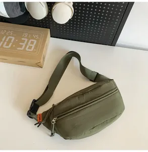 Dettaglio del marsupio in nylon verde oliva con due cerniere ed etichetta arancione