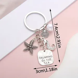 Close-up of ocean-themed keychain with starfish and seahorse charms and size markings.
