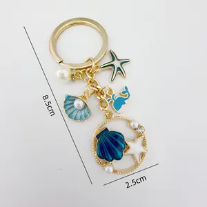 Detail view of the gold-plated ocean theme keychain featuring seashell and starfish charms