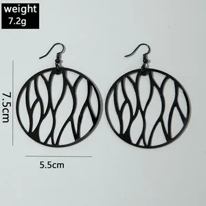 Close-up of black irregular circular cutout drop earrings with geometric design style