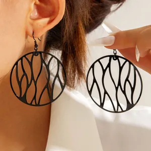 Detail shot showing the intricate black irregular hollow branch pattern on circular drop earrings