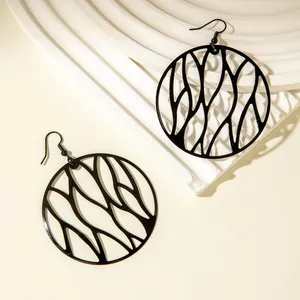 Artistic black irregular hollow geometric circle drop earrings on white plaster display