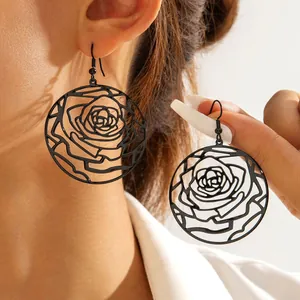 Close-up showing the intricate black hollow rose pattern on circular dangle earrings.
