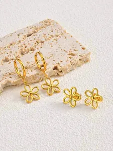 Gros plan détaillé sur des boucles d'oreilles fleur évidée en acier doré sur pierre