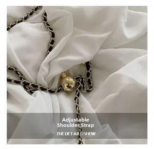 Detail of adjustable golden metal ball and woven chain strap for shoulder bag