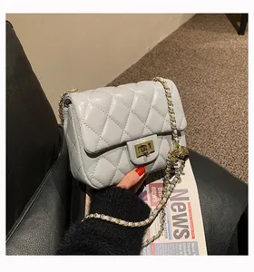 Detailed view of grey quilted leather chain bag with gold metal ball and twist lock