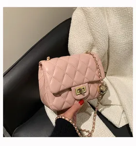 Detail of pink quilted leather bag with gold chain strap and decorative golden ball