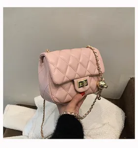 Detail of light pink quilted bag with gold chain strap and metal ball pendant