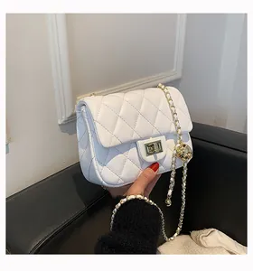 Detailed view of white quilted leather bag with gold ball chain and square turn-lock