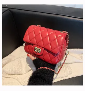 Macro shot of red quilted crossbody bag featuring golden turn-lock and chain strap