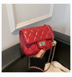 Close-up of red quilted leather handbag with gold ball charm and chain strap