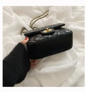 Detail view of the black quilted texture and golden square twist-lock on the chain bag