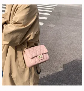 Close-up of a pink quilted crossbody bag with gold chain and metal lock on a model