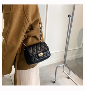 Classic black quilted leather crossbody bag with gold chain strap shown on a model