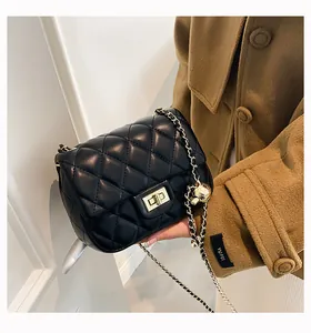 Detail of black quilted leather bag with gold ball chain strap and metallic closure
