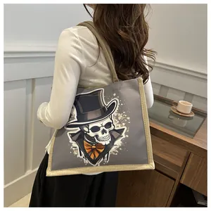 Close-up of a canvas tote bag featuring a skull with a top hat and orange bow tie