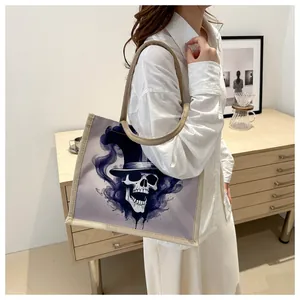Detail of canvas tote bag featuring purple skull print and brown burlap shoulder strap