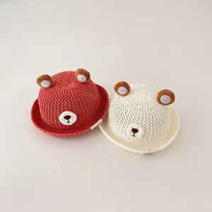 Close-up of red and cream baby straw sun hats featuring adorable bear ear details