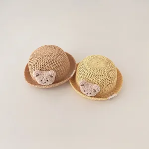 Detailed view of two woven straw sun hats for babies with cute plush bear patches