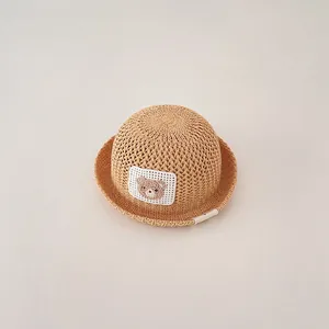 Close-up detail of breathable children's straw sun hat with cute teddy bear patch