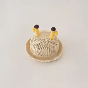 Close-up of a breathable children's straw sun hat with cute plush horn decorations.