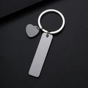 Close-up of a polished stainless steel rectangle tag and heart charm on a metal keychain