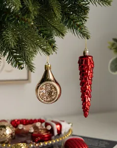 Close-up of golden teardrop and red icicle ornaments hanging on a Christmas tree