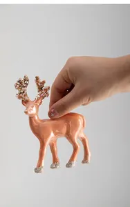 Close-up of metallic orange Christmas deer ornament with glitter and pearl details