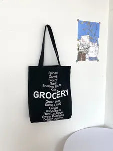Close-up of black canvas tote bag featuring white GROCERY print and vegetable list