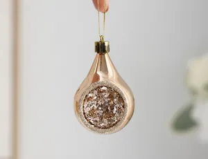 Detail of champagne gold teardrop Christmas ornament with glitter center and glossy finish