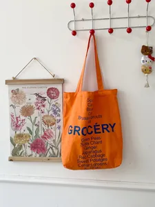 Detail of orange canvas tote bag with blue Grocery text and vegetable names list