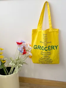 Detail of yellow canvas grocery tote bag with green vegetable print and floral decor