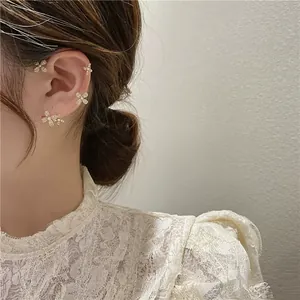 Ensemble de boucles d'oreilles fleurs dorées avec perles et cristaux sur un mannequin