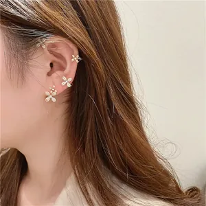 Parure de boucles d'oreilles fleur dorée avec zircons et perles sur un modèle